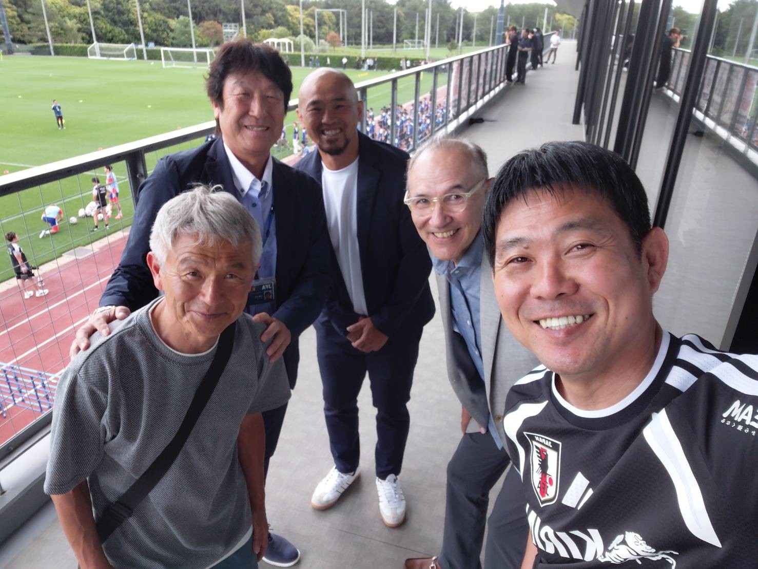 サッカー施設を背景に仲間と写る宮澤ミシェル